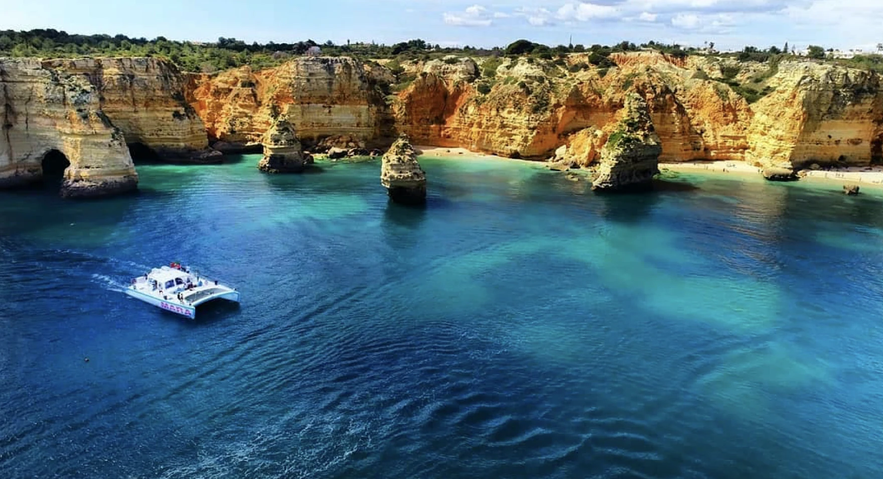 A private yacht exploring the Algarve's golden sea cliffs